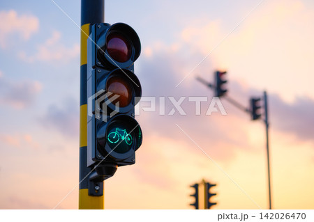 Green bicycle traffic light glowing against a sunset sky. Green bicycle traffic light glowing against a sunset sky. 142026470