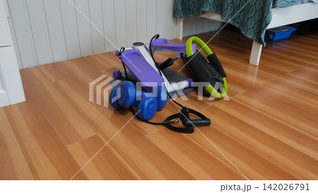 Sport Home exercise equipment. Efficient workout routine. Fitness gear placed for home fit. Yoga mat, roller, dumbbells on room floor ready for recovery session. Personal inventory for weight loss 142026791
