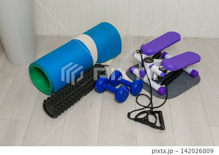 Sport Home exercise equipment. Efficient workout routine. Fitness gear placed for home fit. Yoga mat, roller, dumbbells on room floor ready for recovery session. Personal inventory for weight loss 142026809