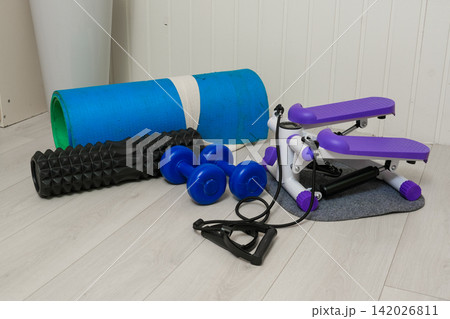 Sport Home exercise equipment. Efficient workout routine. Fitness gear placed for home fit. Yoga mat, roller, dumbbells on room floor ready for recovery session. Personal inventory for weight loss 142026811