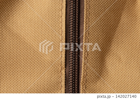 Zipper on a tan fabric bag with detailed stitching Zipper on a tan fabric bag with detailed stitching 142027140