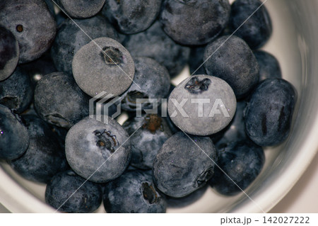 Macro shot of frozen fresh blueberries with hoarfrost frost layer in a bowl 142027222