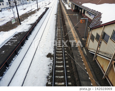 冬のローカル線駅ホームと積雪する線路を上から見下ろすアングル 142028069