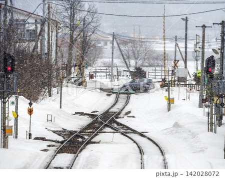 雪の降る踏切と線路の分岐点・冬の地方鉄道路線の風景 雪の降る踏切と線路の分岐点・冬の地方鉄道路線の風景 142028072