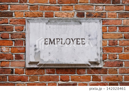 Employee word on a stone plaque on a red brick wall 142028461