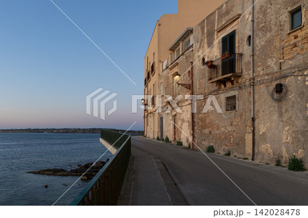 morning dusk waterfront street along sea with old stone building and blue purple sky background morning dusk waterfront street along sea with old stone building and blue purple sky background 142028478