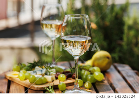 Garden Wine Tasting with White Wine, Grapes, and Cheese Platter Garden Wine Tasting with White Wine, Grapes, and Cheese Platter 142028524