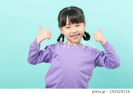 A joyful little girl in a lavender pullover smiling brightly while pointing her thumbs at herself in a confident manner. A joyful little girl in a lavender pullover smiling brightly while pointing her thumbs at herself in a confident manner. 142029158