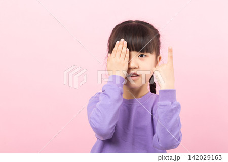 A serious young student covering one eye with her hand while pointing her other pinky finger to the up. A serious young student covering one eye with her hand while pointing her other pinky finger to the up. 142029163