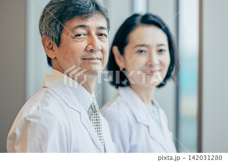 研究施設の窓際で外を眺める白衣姿の男女研究者 研究施設の窓際で外を眺める白衣姿の男女研究者 142031280