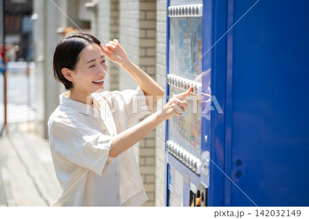 自動販売機で飲み物を買う女性 142032149