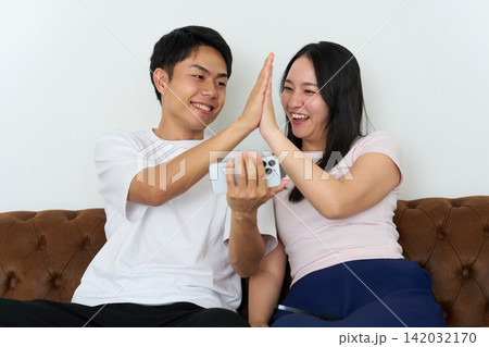 スマートフォンを見ながら熱狂する若い男女 スマートフォンを見ながら熱狂する若い男女 142032170