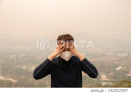 Asian woman having headache becaused of by Bad air pollution (PM2.5). PM2.5 levels meaning the air quality posed a health hazard. Asian woman having headache becaused of by Bad air pollution (PM2.5). PM2.5 levels meaning the air quality posed a health hazard. 142032507
