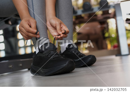 A woman ties her shoelaces ready to run at the gym. 142032705