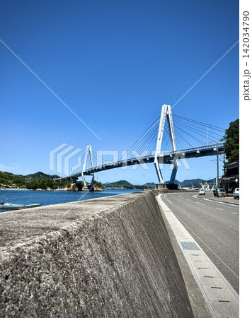 海沿いの道路と防波堤から望む弓削大橋（ゆめしま海道・愛媛県上島町） 142034790
