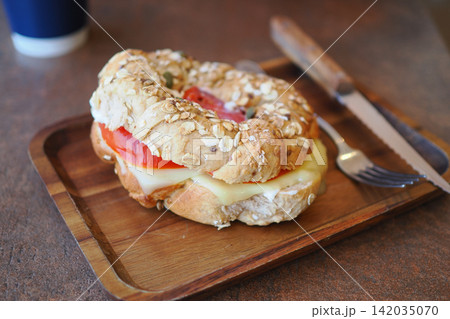 Fresh bagel with cheese and tomato on wooden tray Fresh bagel with cheese and tomato on wooden tray 142035070