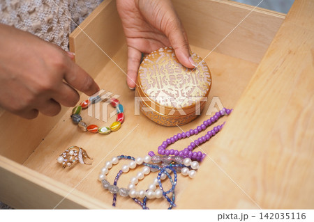 Jewelry is being organized in a wooden drawer Jewelry is being organized in a wooden drawer 142035116