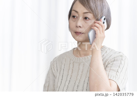 リビングでスマホで喋るシニア女性 142035779