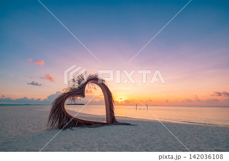 Enchanting heart shaped palm silhouette vivid dusk glowing sea warm reflected horizon. Summer honeymoon travel seascape scenic. Exotic couples getaway wall art decor Enchanting heart shaped palm silhouette vivid dusk glowing sea warm reflected horizon. Summer honeymoon travel seascape scenic. Exotic couples getaway wall art decor 142036108