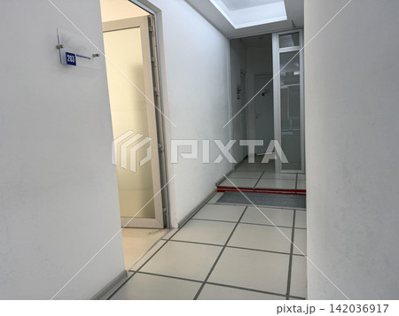 A waiting area shows a brown bench along the wall a trash can beside it and two doors A waiting area shows a brown bench along the wall a trash can beside it and two doors 142036917