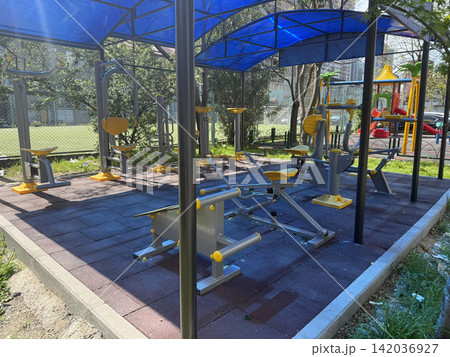 Four pieces of outdoor gym equipment stand in a park Four pieces of outdoor gym equipment stand in a park 142036927