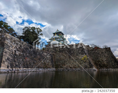 雲間から差し込む光に照らされた大阪城天守閣と広大な石垣の風景 雲間から差し込む光に照らされた大阪城天守閣と広大な石垣の風景 142037350