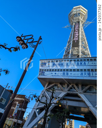 冬の澄み渡る青空にそびえ立つ大阪のランドマーク通天閣と都会のビル群 冬の澄み渡る青空にそびえ立つ大阪のランドマーク通天閣と都会のビル群 142037362