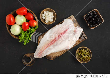 Fresh pangasius fish fillet and vegetables on wooden cutting board in kitchen 142037427