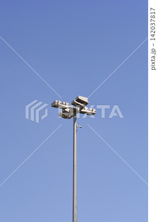 Stadium floodlight tower with security camera against blue sky Stadium floodlight tower with security camera against blue sky 142037817