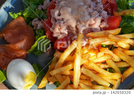 Fresh meal with seafood salad, golden fries, smoked delicacy, vibrant green salad, and boiled egg close-up Fresh meal with seafood salad, golden fries, smoked delicacy, vibrant green salad, and boiled egg close-up 142038320