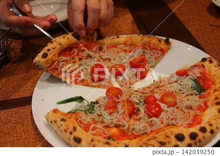 レストランでピザをシェアして楽しむ食事の風景 レストランでピザをシェアして楽しむ食事の風景 142039250
