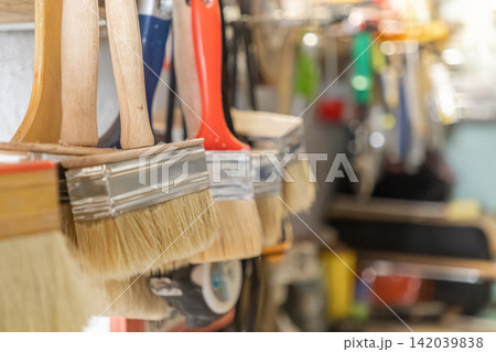 Paintbrushes hang neatly in a row on a workshop wall, representing professional renovation equipment and home improvement projects prepared for skilled manual labor and diy creativity Paintbrushes hang neatly in a row on a workshop wall, representing professional renovation equipment and home improvement projects prepared for skilled manual labor and diy creativity 142039838