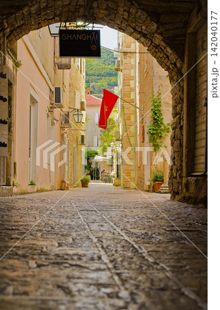 Historic Budva alley with stone archway and a flag in Montenegro Historic Budva alley with stone archway and a flag in Montenegro 142040177