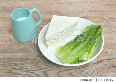hamcheese sandwich with fresh cos lettuce on plate eat couple fresh milk cup hamcheese sandwich with fresh cos lettuce on plate eat couple fresh milk cup 142041045