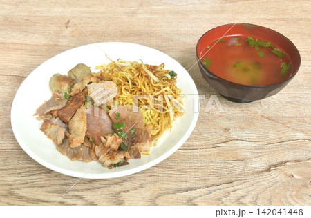 dry boiled Chinese yellow egg noodles with braised beef and meatball dressing black sweet soy sauce on plate with soup 142041448