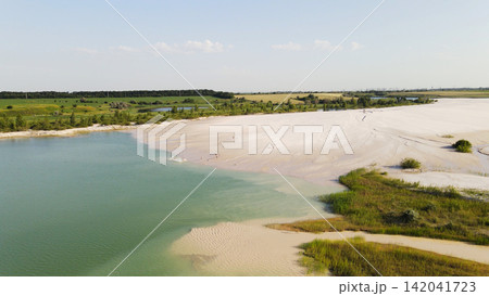 Industrial waste leaving polluted water and sandy shore against a green landscape and blue sky Industrial waste leaving polluted water and sandy shore against a green landscape and blue sky 142041723