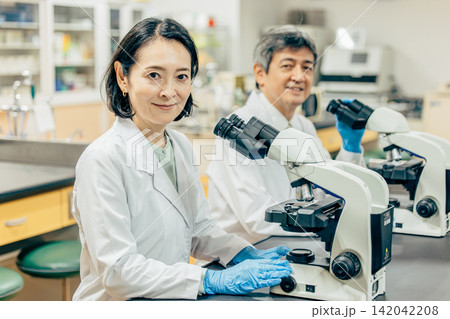 実験室で顕微鏡を使用して研究を行う研究者 実験室で顕微鏡を使用して研究を行う研究者 142042208