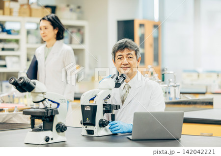 実験室で顕微鏡を使用して研究を行う研究者 実験室で顕微鏡を使用して研究を行う研究者 142042221