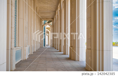 Long symmetrical corridor with tall white columns and arches perspective of Nursultan mosque 142042385