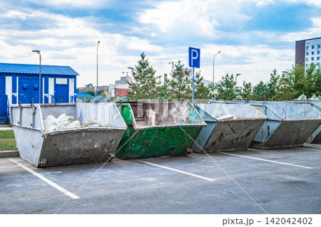 Row of construction waste containers in parking area Row of construction waste containers in parking area 142042402