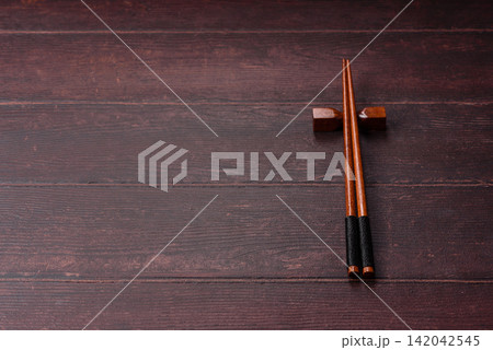 Asian style chopsticks on a dark, empty wooden table. Chopsticks as a food background 142042545