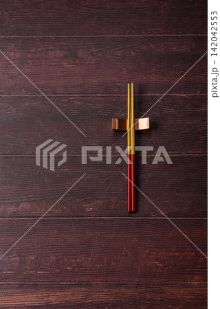 Asian style chopsticks on a dark, empty wooden table. Chopsticks as a food background Asian style chopsticks on a dark, empty wooden table. Chopsticks as a food background 142042553
