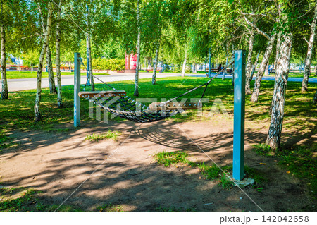 Net hammock swing in birch tree summer park, outdoor leisure lifestyle concept Net hammock swing in birch tree summer park, outdoor leisure lifestyle concept 142042658