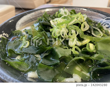 器いっぱいに盛り付けられたたっぷりのワカメと刻みネギの温かいわかめうどん 器いっぱいに盛り付けられたたっぷりのワカメと刻みネギの温かいわかめうどん 142043280