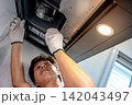 Asian male technician using screwdriver fixing extractor motor in cooker hood 142043497