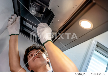 Asian male technician using screwdriver fixing extractor motor in cooker hood 142043497