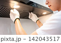 Asian male maintenance worker repairing modern cooker hood in domestic kitchen 142043517