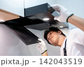 Asian male technician removing range hood filter looking at exhaust fan inside the cooker hood 142043519