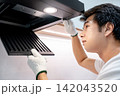 Asian male technician removing range hood filter looking at exhaust fan inside the cooker hood 142043520