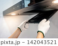 Male hand with protective gloves removing black range hood filter from cooker hood 142043521